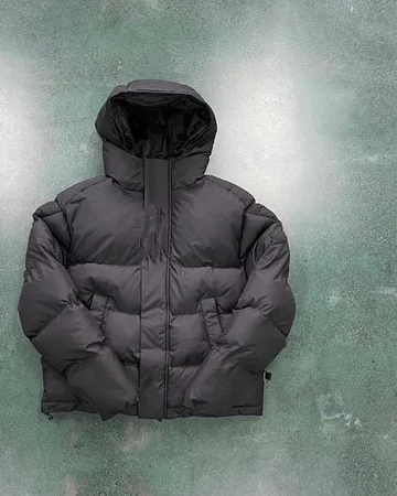 Charcoal hooded puffer jacket laid flat on a green concrete floor